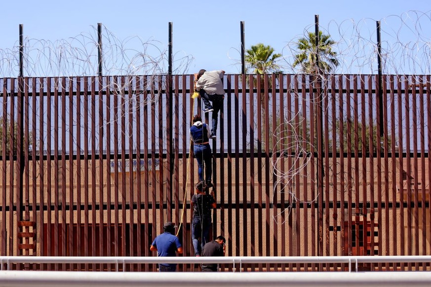 MEXICALI, BAJA CALIFORNIA - MAY 13: Migrants attempt to climb over the border wall from Mexicali, Mexico to Calexico, USA, along the U.S.-Mexico border near the port of entry on Saturday, May 13, 2023 ...