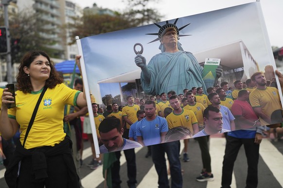A woman stands next to a banner with a generated image of U.S. President Donald Trump, during a demonstration to protest Brazil&#039;s former President Jair Bolsonaro&#039;s Supreme Court trial for al ...