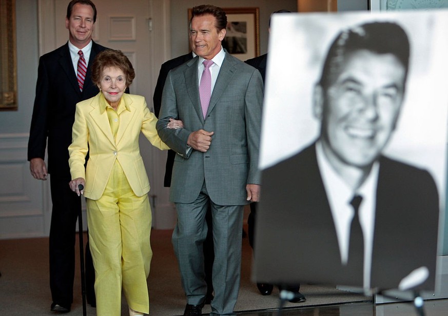 California Governor Arnold Schwarzenegger assists former first lady Nancy Reagan as they walk in for a ceremonial bill signing for SB 944 and AB 1911 at the Ronald Reagan Library in Simi Valley July 2 ...
