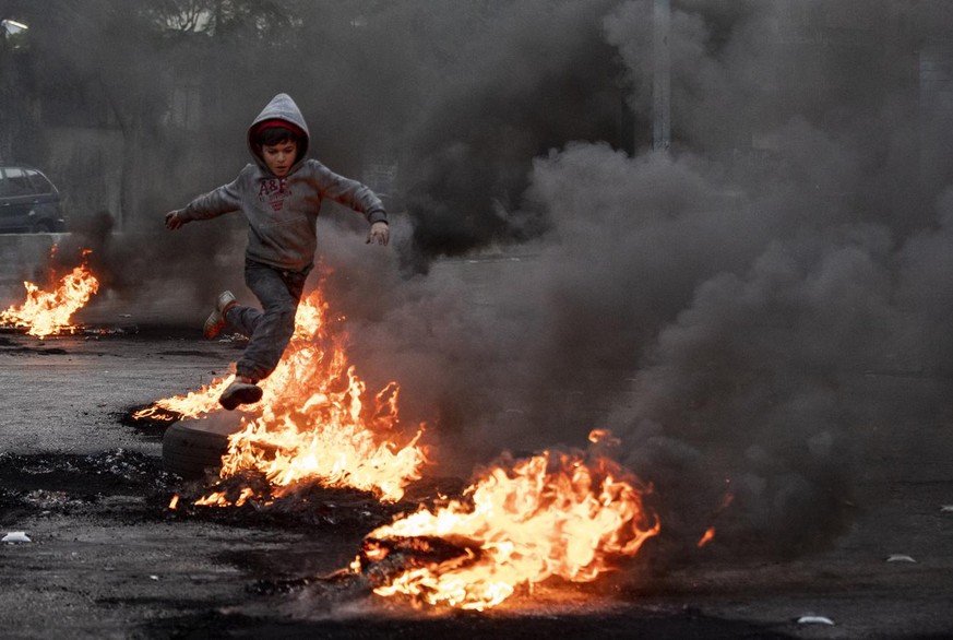 A boy jumps over burning tires that were set on fire to block a road, during a protest in Beirut, Lebanon, Tuesday, March 2, 2021. Scattered protests broke out in different parts of Lebanon Tuesday af ...