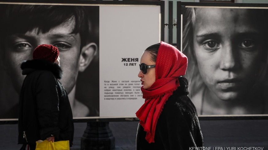 Des personnes passent devant des photos exposées dans le cadre de l&#039;exposition &quot;Regarder dans les yeux du Donbass&quot; à Moscou, Russie, le 17 mars 2022. EPA/YURI KOCHETKOV