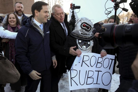 Un manifestant du mouvement progressiste Americans United for Change, en 2016, déguisé en robot. A gauche, Marco Rubio, qui n’avait pas perdu son sourire.