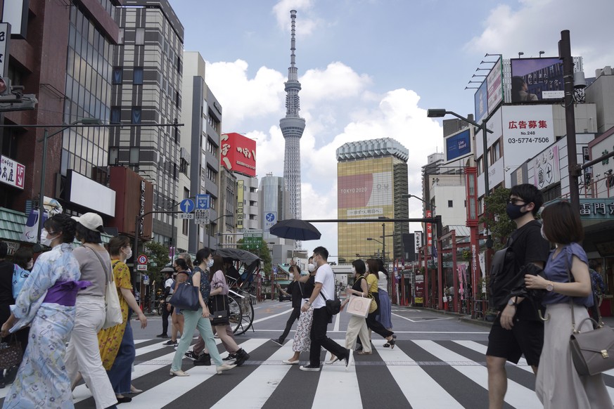 FILE - People walk along a pedestrian crossing in the tourist district of Asakusa, near the landmark Tokyo Skytree tower in Tokyo, Japan on July 31, 2021. Individual travelers will be able to visit Ja ...
