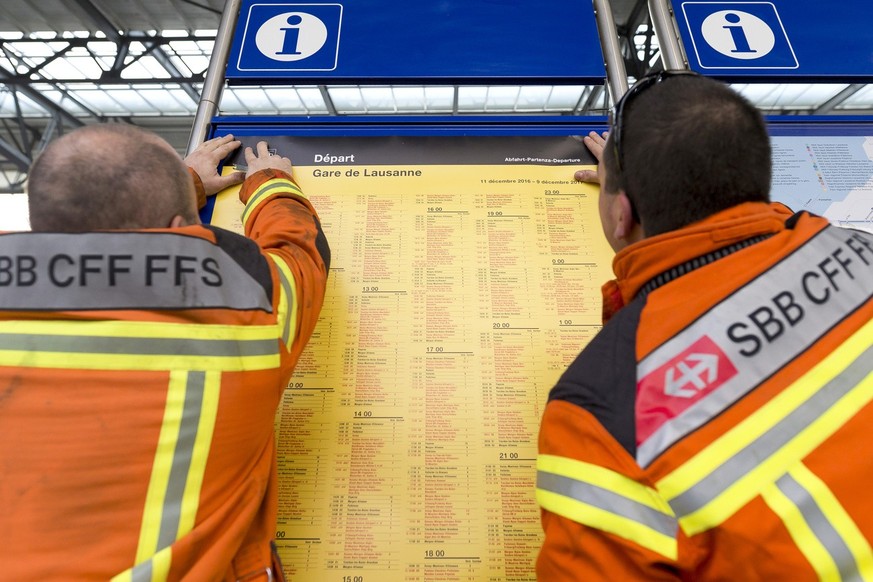 Des employes des chemins de fer federaux (CFF) changent les affiches horaire des panneaux sur le quais de la gare de Lausanne ce vendredi 9 decembre 2016. Les nouveaux horaires des CFF entreront en vi ...