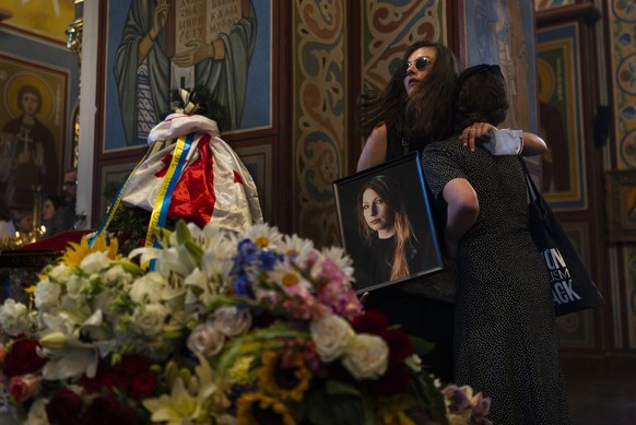 Holding a photo of Ukrainian writer Victoria Amelina, Sofia Cheliak hugs a woman during a memorial service for Amelina in Kyiv, Ukraine, Tuesday, July 4, 2023. The award-winning writer died from her i ...