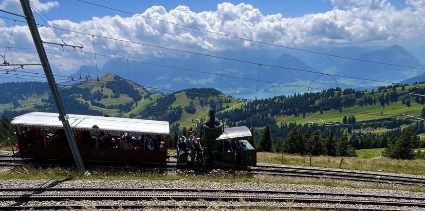 La locomotive no 7 de la ligne du Rigi, avec son wagon d'époque. Des passagers ont pris place sur la plateforme de la locomotive, derrière la chaudière verticale.