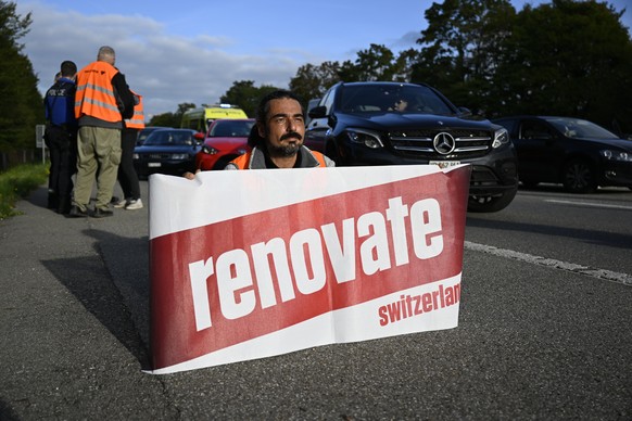 Environmental activists members of Renovate Switzerland sit down in the road during a roadblock action of the A1 motorway, in Lausanne, Switzerland, Tuesday, October 4, 2022.(KEYSTONE/Laurent Gilliero ...