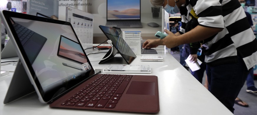 epa09095418 A visitor inspects Microsoft Surface Laptop Go at a computer show and sales event Commart Thailand 2021 in Bangkok, Thailand, 25 March 2021. Hundreds of exhibitors, Information Technology  ...