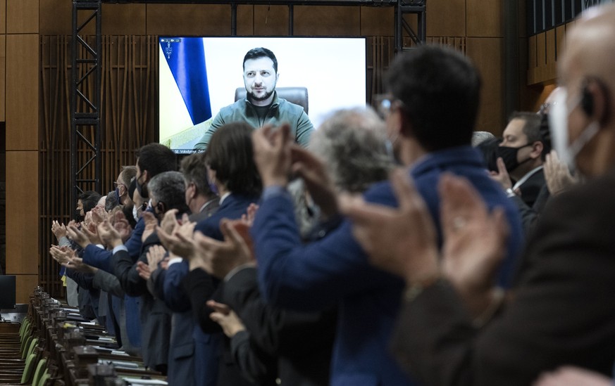Canadian Members of Parliament and invited guests applaud as Ukrainian President Volodymyr Zelenskyy is shown on a giant video screen before addressing the Canadian parliament, Tuesday, March 15, 2022 ...