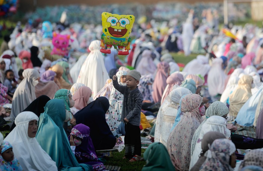 epa09921902 Indonesian Muslim children play with balloons during Eid al-Fitr prayers at a field in Depok, Indonesia, 02 May 2022. Muslims around the world are celebrating Eid al-Fitr, the three day fe ...