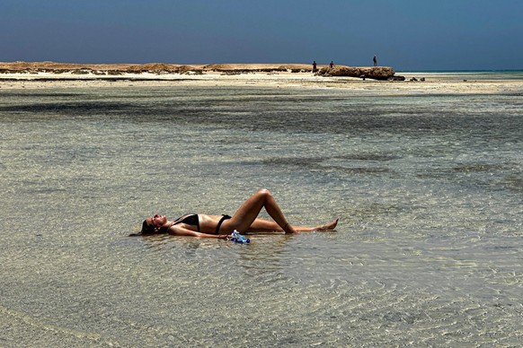 (FILES) A tourist lies on shallow water at the Ras Hankorab beach in the Red Sea Wadi Al-Gemal protectorate in southern Egypt on May 28, 2025. Wadi al-Gemal National Park, declared a protected area in ...