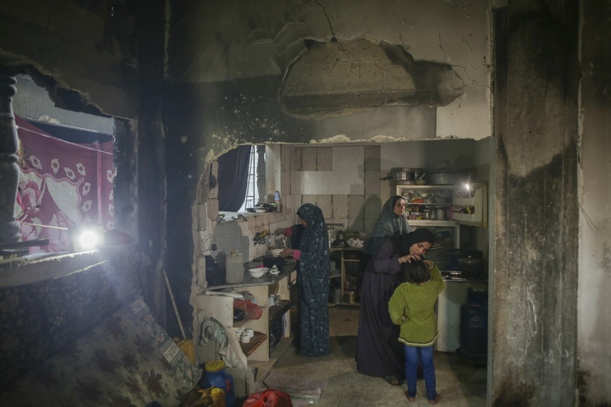 Fatima Al-Absi, center left, prepares food for her family's iftar, the fast-breaking meal, on the first day of Ramadan in their damaged apartment in Jabaliya, northern Gaza Strip, on Saturday, Ma ...