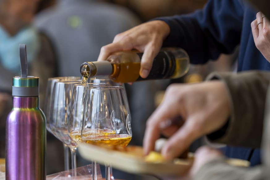 Une visiteuse sert du vin blanc dans des verres durant la 64e edition de la Foire du Valais, ce dimanche 6 octobre 2024 a Martigny. (KEYSTONE/Salvatore Di Nolfi)