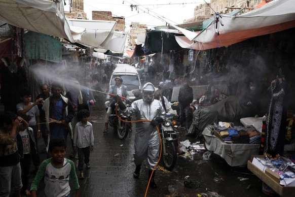epa08394051 A Yemeni worker (C) wearing a protective suit sprays disinfectant at a market amid the ongoing coronavirus COVID-19 pandemic in Sanaa, Yemen, 30 April 2020. Two people have died from COVID ...