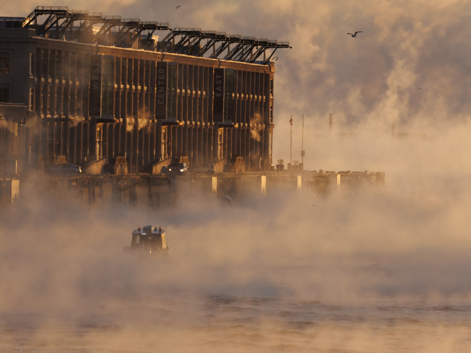 epa10446999 A lobster boat heads out as sea smoke, forms over the water of Boston Harbor, in Boston, Massachusetts, USA, 04 February 2023. Sea smoke, or steam fog, forms when cold air flows immediatel ...