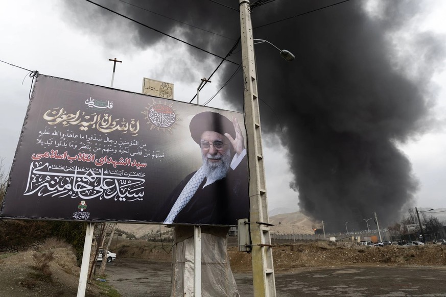 Portrait du chef de la Révolution Ali Khamenei devant le dépôt pétrolier de Shahran en feu à Téhéran.