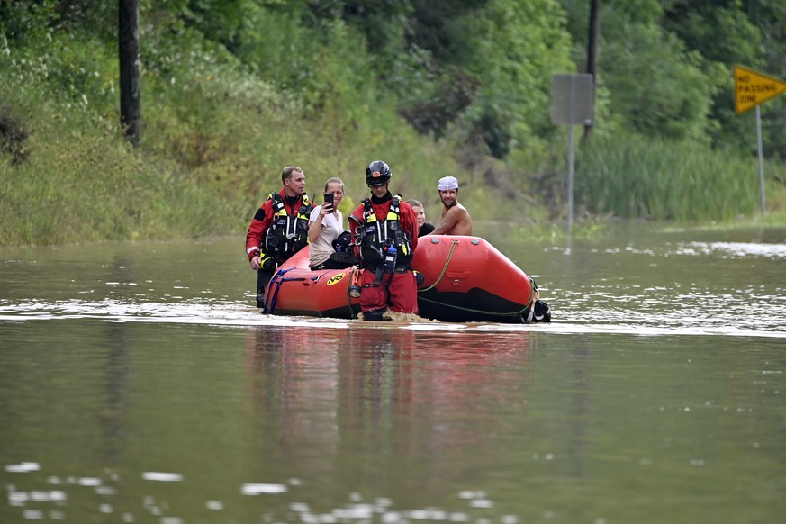Members of the Winchester, Ky., Fire Department walk inflatable boats across flood waters over Ky. State Road 15 in Jackson, Ky., to pick up people stranded by the floodwaters Thursday, July 28, 2022. ...