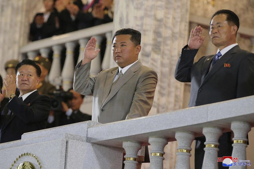 In this photo provided by the North Korean government, North Korean leader Kim Jong Un, center, waves from a balcony toward the assembled troops and spectators during a celebration of the nation��&amp ...