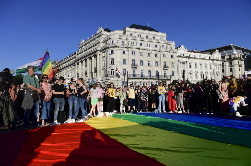 Des gens déploient un drapeau arc-en-ciel lors d&#039;une manifestation pour les droits des LGBT devant le Parlement hongrois à Budapest, en Hongrie, en juin. 14, 2021.