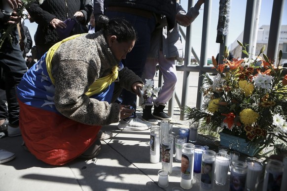 A woman places flowers in front of a gate that has been converted into a makeshift memorial, outside a Mexican immigration detention center in Ciudad Juarez, Mexico, Tuesday, March 28, 2023, where a f ...