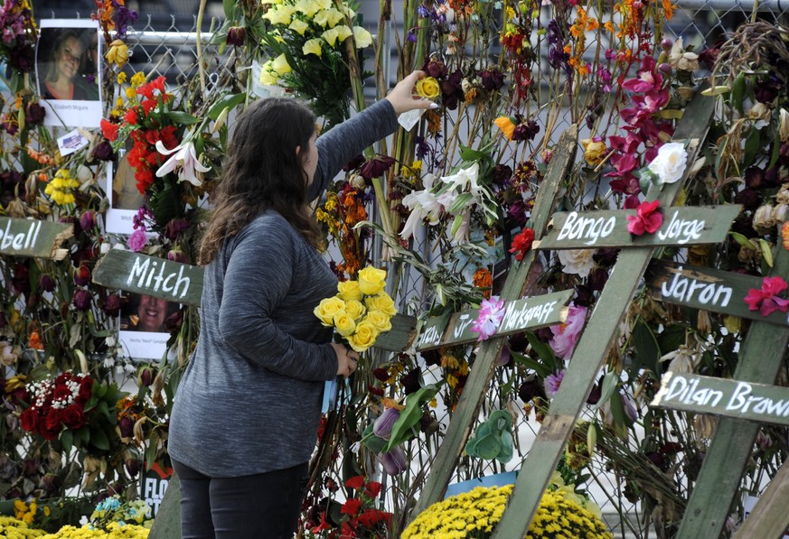 Holly Harmon places a rose into a memorial for victims of Hurricane Ian in Fort Myers, Fla., on Monday, Oct. 10, 2022. More than 100 died during the hurricane, with the greatest number in Lee County.  ...