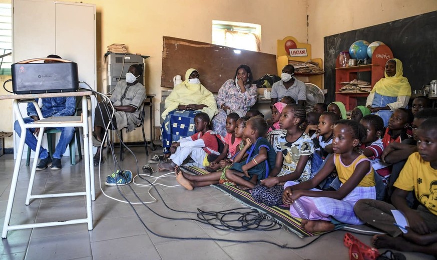 A Dakar, des élèves suivent la télévision par satellite via un projecteur offert par StarTimes dans un projet financé par la Chine (22 nov. 2021).