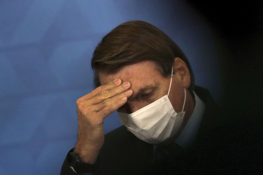 Brazil&#039;s President Jair Bolsonaro, wearing protective face mask, listens during a ceremony announcing economic measures to support philanthropic hospitals and help them treat COVID-19 patients, a ...