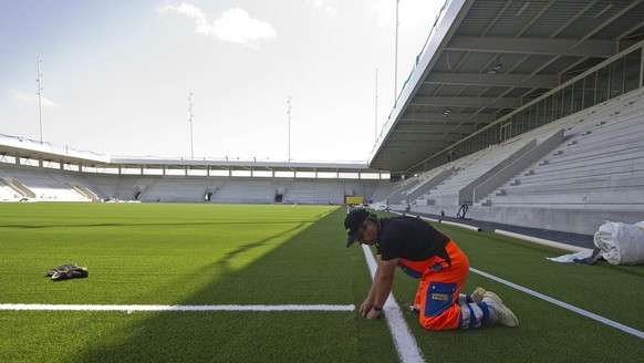 Ein Arbeiter verlegt den Kunstrasen im neuen Fussballstadion &quot;Arena Thun&quot;, am Freitag 13. Mai 2011, in Thun. (KEYSTONE/Peter Schneider)