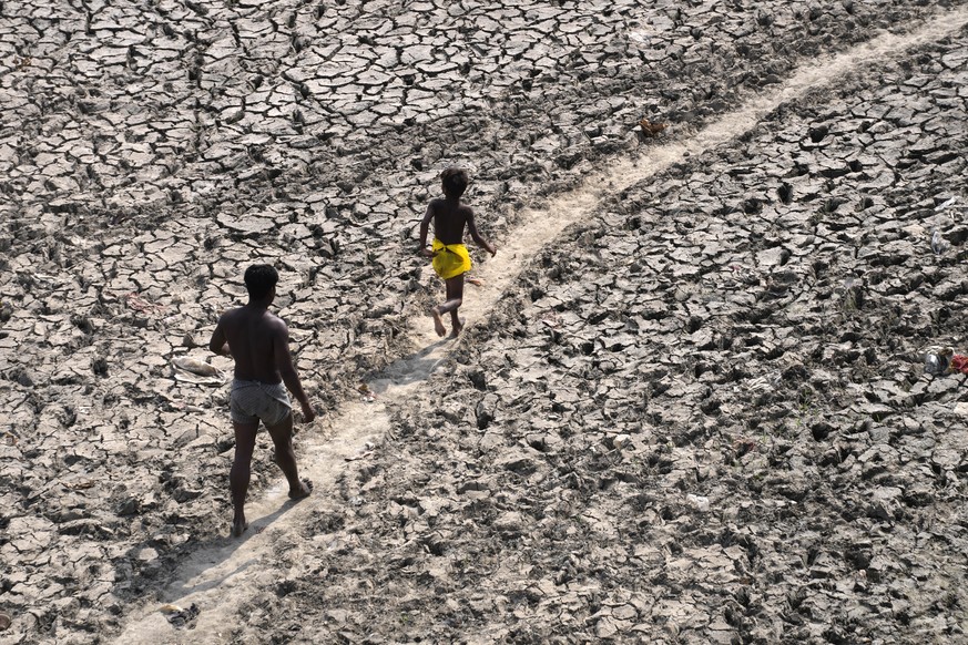 A man and a boy walk across an almost dried up bed of river Yamuna following hot weather in New Delhi, India, Monday, May 2, 2022. An unusually early and brutal heat wave is scorching parts of India,  ...