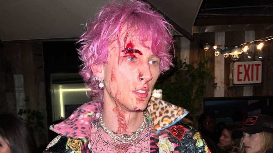 MGK, debout sur une table, s&#039;est explosé une flute de champagne sur le visage.