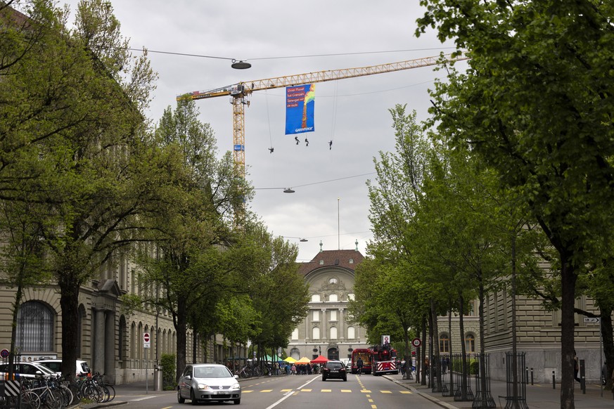 Greenpeace-Aktivisten entrollen am Swiss Overshoot Day auf dem Baukran auf der Baustelle der Nationalbank ein Transparent, am Samstag, 13. Mai 2023, auf dem Bundesplatz in Bern. (KEYSTONE/Peter Klaunz ...