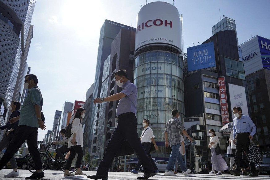 People wearing protective masks to help curb the spread of the coronavirus walk along a pedestrian crossing Tuesday, Oct. 5, 2021, in Tokyo. (AP Photo/Eugene Hoshiko)