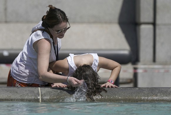 A person wets their hair in a fountain at Trafalgar Square in central London, Tuesday July 19, 2022. Millions of people in Britain woke from the country���s warmest-ever night on Tuesday and braced fo ...