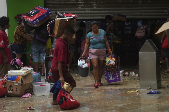 Des personnes pillent une épicerie après le passage de l'ouragan Otis.
