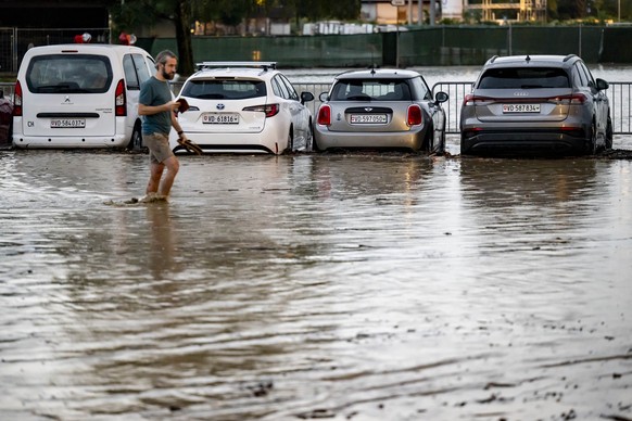 Une personne marche entre des vehicules sur un parking inonde suite a un orage qui a entraine une importante inondation dans le centre ville le mardi 25 juin 2024 a Morges. (KEYSTONE/Laurent Gillieron ...