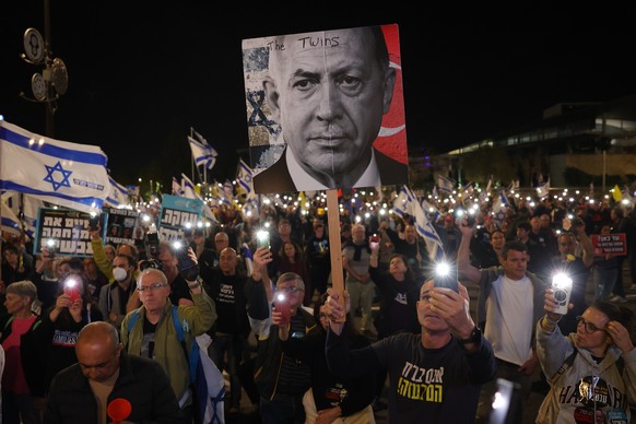 epa12001885 An anti-government protester supporting families of Israeli hostages held by Hamas in Gaza, holds a poster with a picture montage of Israeli Prime Minister Netanyahu and Turkish President  ...