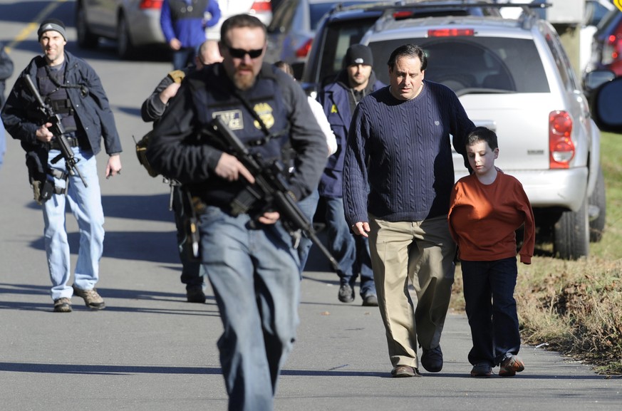 FILE- In this Dec. 14, 2012 file photo, parents leave a staging area after being reunited with their children following a shooting at the Sandy Hook Elementary School in Newtown, Conn. At least 14 chi ...