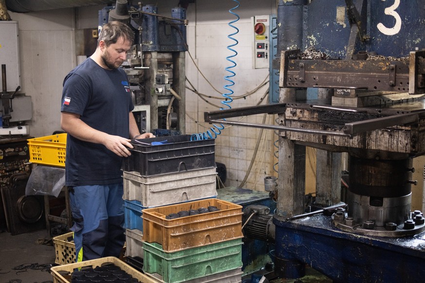 An employee of the Czech company Gufex working on the production of ice hockey pucks for the 2026 Olympic Games checks souvenir pucks with a printed logo of the Games at the factory in the village of  ...