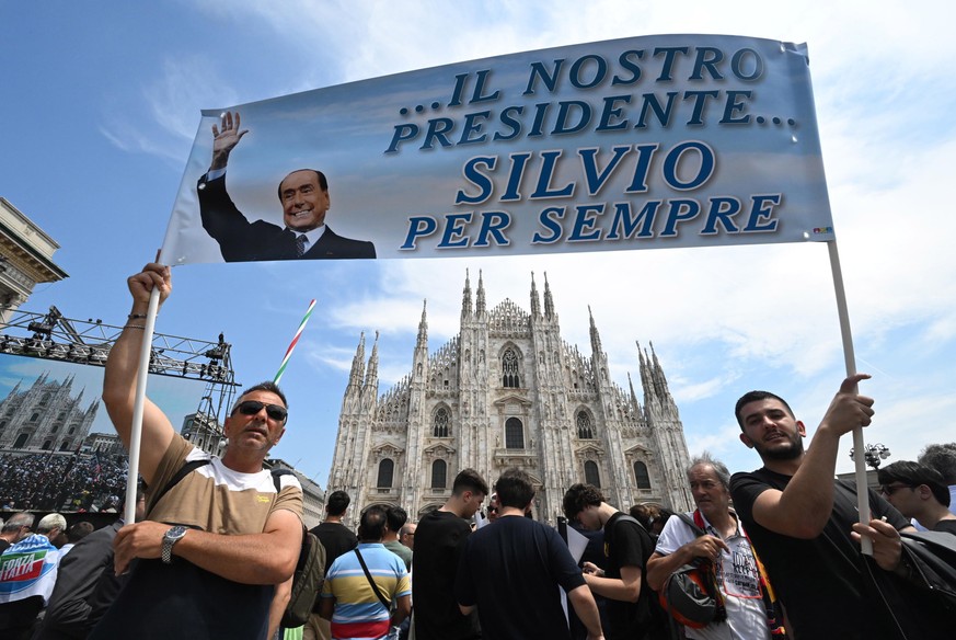 epa10690387 Two persons hold up a banner reading &#039;...our president, Silvio forever&#039; as they wait outside the Milan Cathedral (Duomo) ahead of the state funeral for Italy&#039;s former prime  ...