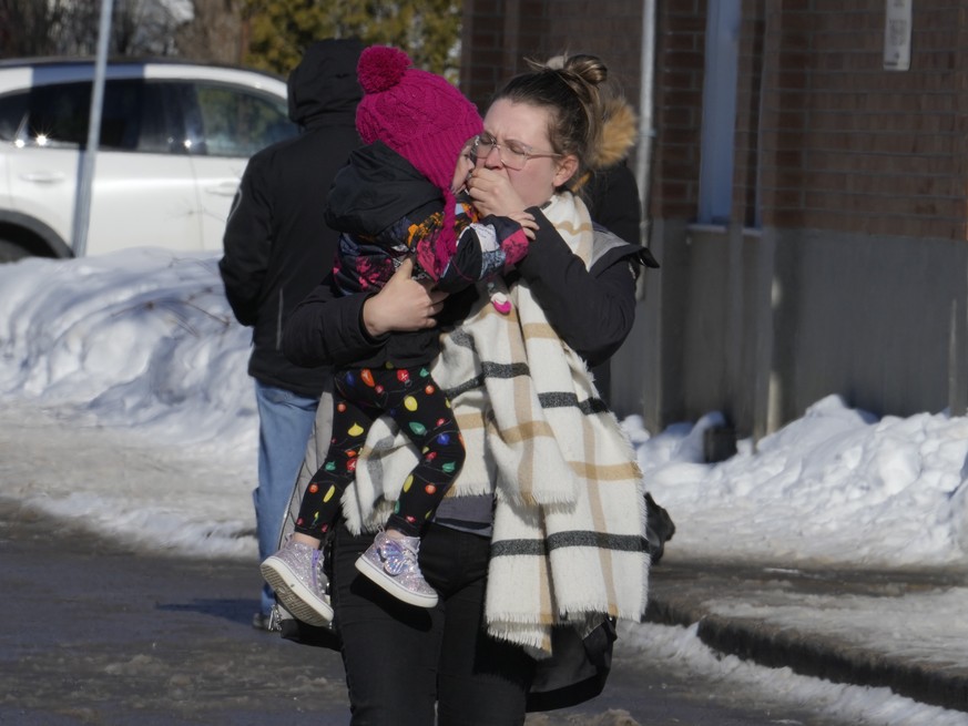 A woman carries a child from a daycare centre after a city bus crashed into the facility in Laval, Quebec, Wednesday, Feb.8, 2023. At least eight people including several children have been sent urgen ...