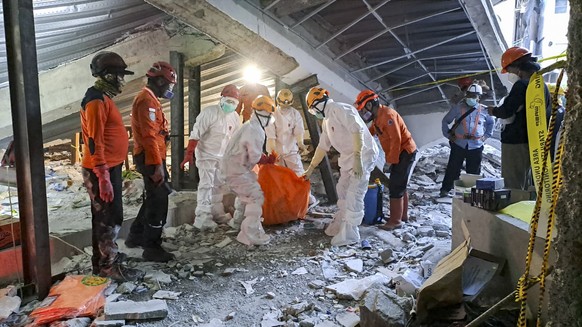 epa12427341 A handout photo made available by Indonesian National Search and Rescue Agency (BASARNAS) shows rerescuers carrying the body of a victim from the rubble of a collapsed building at an Islam ...