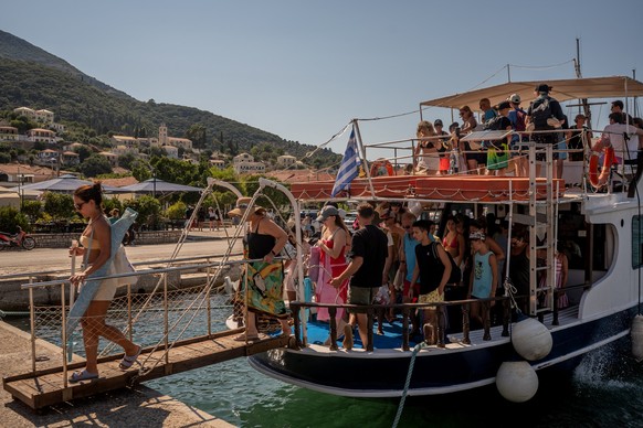 Tourists disembark from a boat after returning from nearby beaches on the island of Ithaca, in the Ionian Sea, on August 3, 2026. Ithaca, the home to the hero Odysseus in Homer's Odyssey, is far  ...