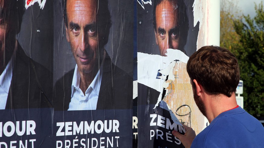 A man tears off posters showing hard-right political talk-show star Eric Zemmour in Biarritz, southwestern France, Tuesday, Oct. 26, 2021. Provocative anti-immigration commentator Eric Zemmour is draw ...
