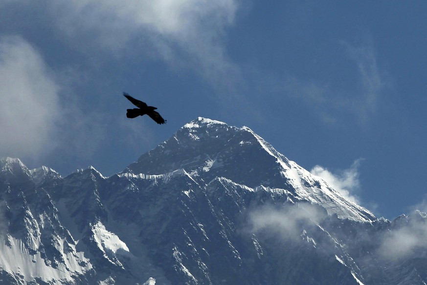 FILE - A bird flies with Mount Everest seen in the background from Namche Bajar, Solukhumbu district, Nepal, May 27, 2019. A helicopter flying out of the Mount Everest area in Nepal carrying foreign t ...