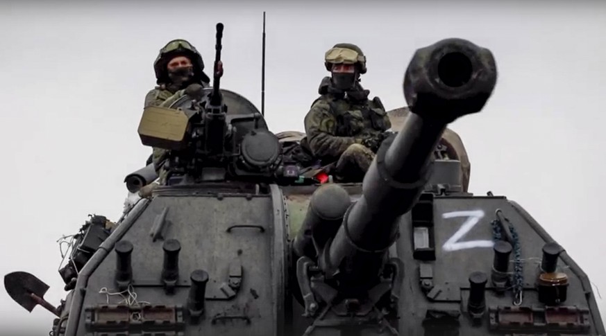 epa09807297 A still image taken from a handout video made available by the Russian Defence Ministry press service shows Russian servicemen drive on a 152mm self-propelled artillery system MSTA-S on th ...