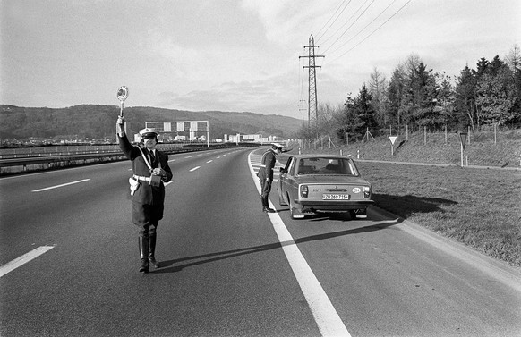 AUTOFREIE SONNTAGE - Eine Polizeipatrouille kontrolliert ein Auto an einem der Autofreien Sonntage im November/Dezember 1973 in der Schweiz. Wegen der unsicheren Versorgungslage auf dem Erdoelmarkt er ...