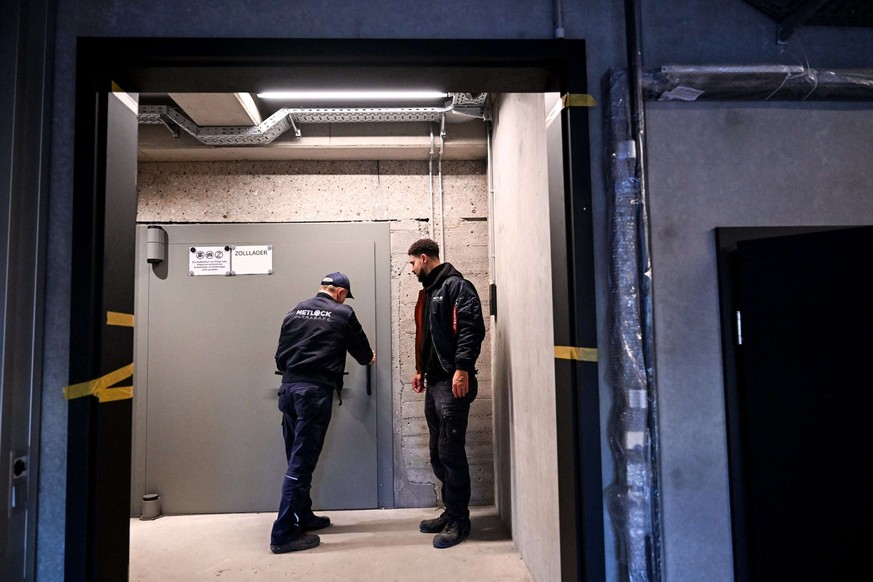 Des employés ferment une imposante porte de sécurité à l&#039;intérieur de la salle de stockage de Tradium.