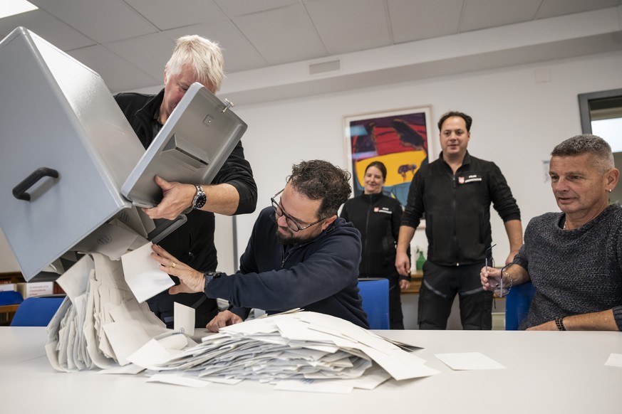 Roland Moritz, policier administratif, gauche, verse les bulletins de vote de l&#039;urne sur la table des membres du bureau de depoillement, le jour des elections au Gouvernement et au Parlement jura ...