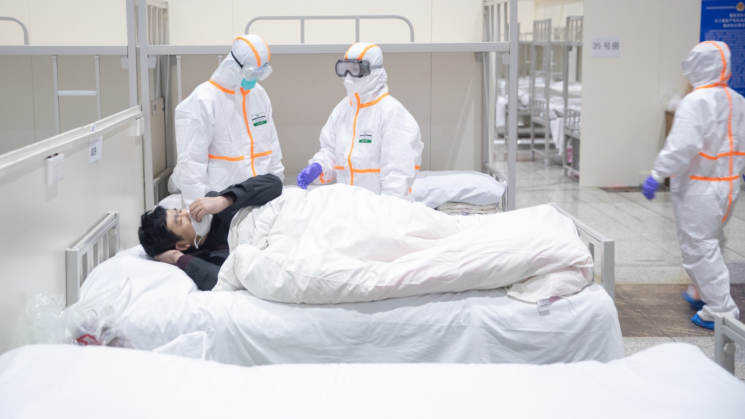 epa08196535 Medical staff attend to a patient infected by the coronavirus at a makeshift hospital at Wuhan International Convention and Exhibition Center in Wuhan City, Hubei Province, China, 05 Febru ...