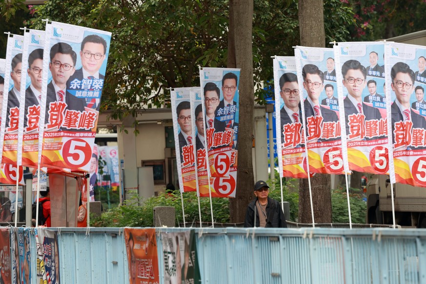 epaselect epa12576285 Citizens walk past election campaign banners in Tai Po district during the Legislative Council General Election in Hong Kong, China, 07 December 2025. Hong Kong&#039;s &#039;patr ...